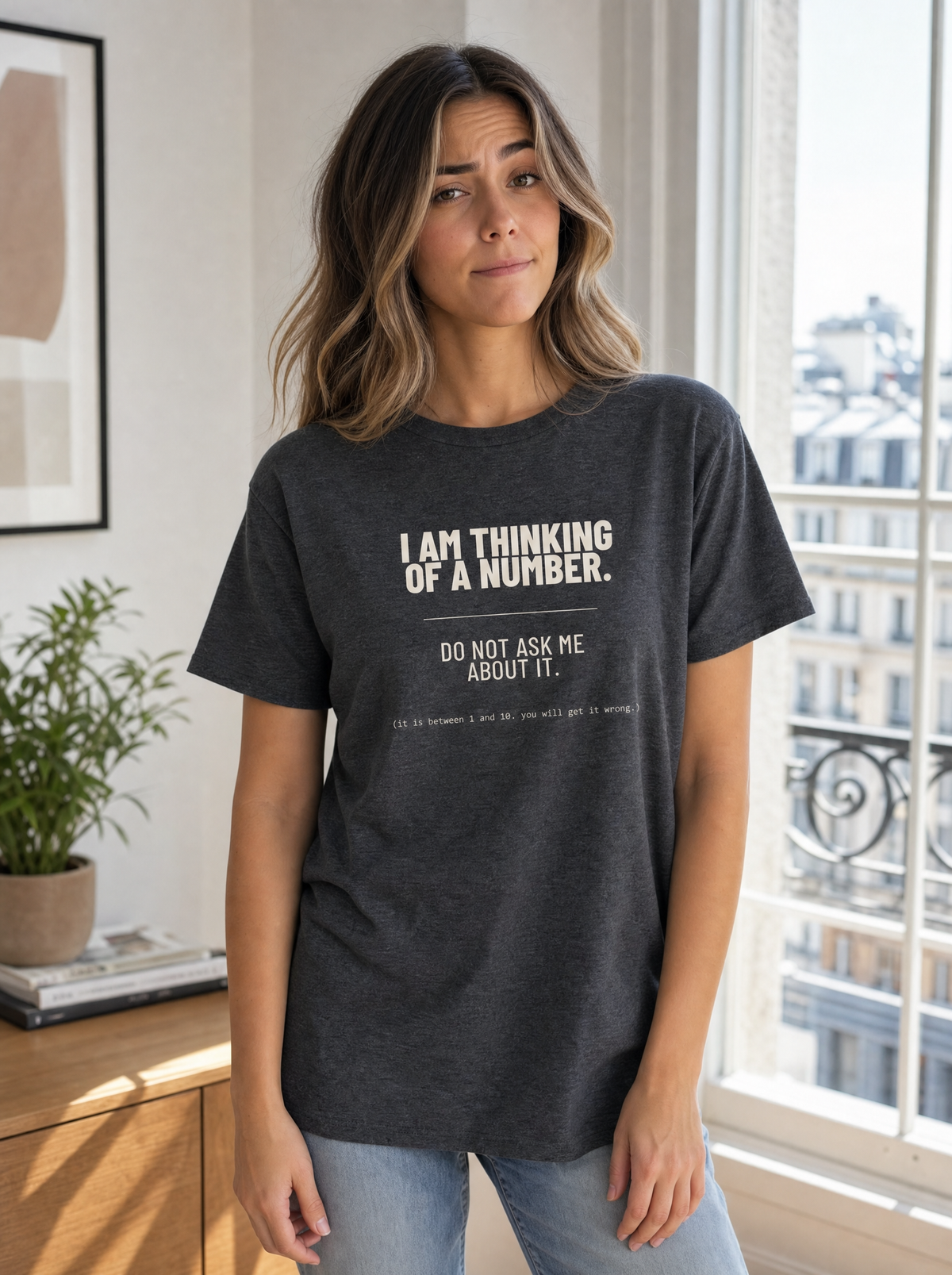 I Am Thinking of a Number tee in black, worn by a woman. Model: Seloura (AI brand character). AI-generated model image; the printed design is the actual product artwork.