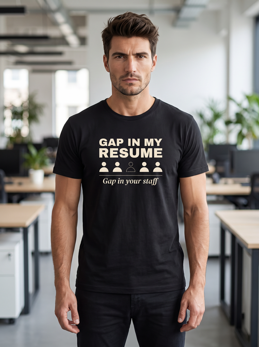 Liora wearing the unisex t-shirt in black with a row of five figures with one missing and cream bold type reading gap in my resume, gap in your staff. Model: Liora (AI brand character). AI-generated model image; the printed design is the actual product artwork.