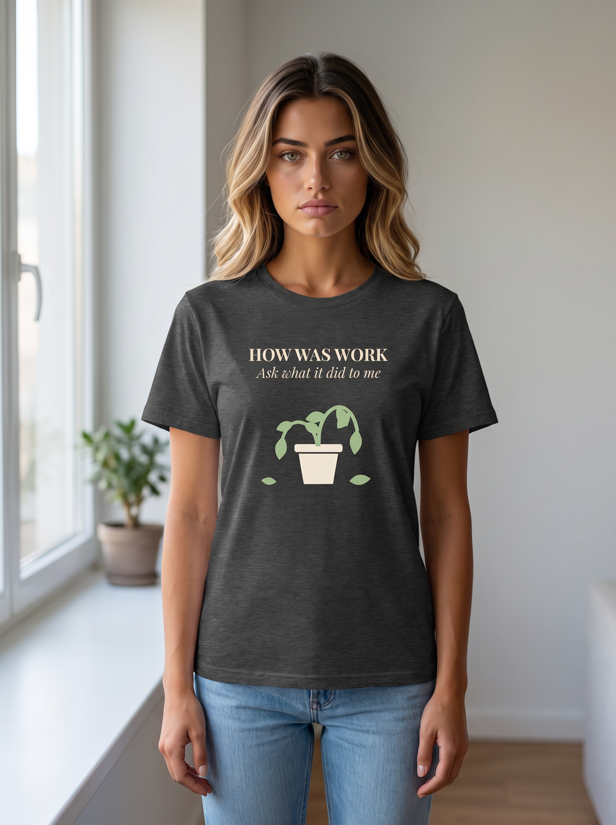 Seloura wearing the unisex t-shirt in dark grey heather with a drawing of a drooping potted plant and cream serif type reading how was work, ask what it did to me. Model: Seloura (AI brand character). AI-generated model image; the printed design is the actual product artwork.