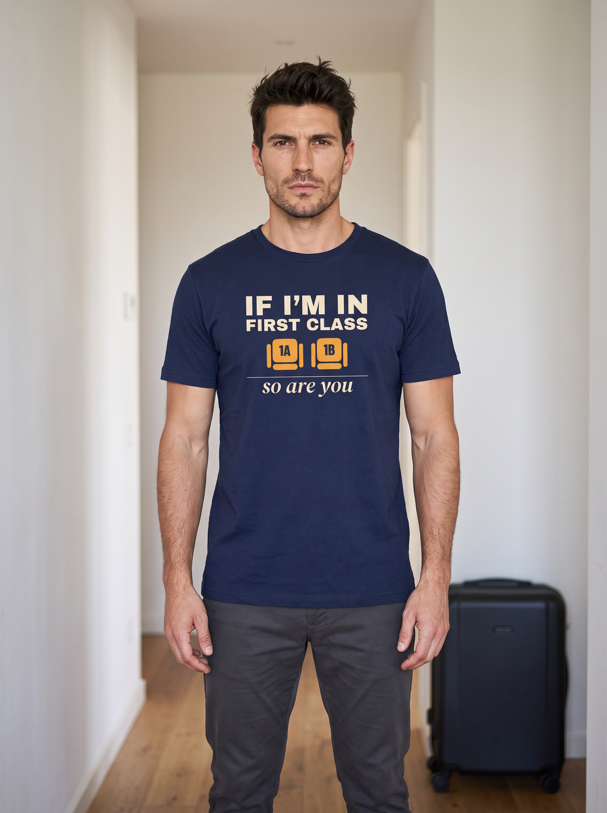 Liora wearing the unisex t-shirt in navy with two wide seats marked 1A and 1B in amber and cream type reading if I'm in first class, so are you. Model: Liora (AI brand character). AI-generated model image; the printed design is the actual product artwork.