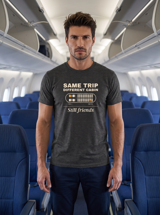 Liora standing in the aisle of an economy aircraft cabin, wearing the unisex t-shirt in dark grey heather with a seat map with one amber seat in row 1 and one in row 34 and cream type reading same trip, different cabin, still friends. Model: Liora (AI brand character). AI-generated model image; the printed design is the actual product artwork.